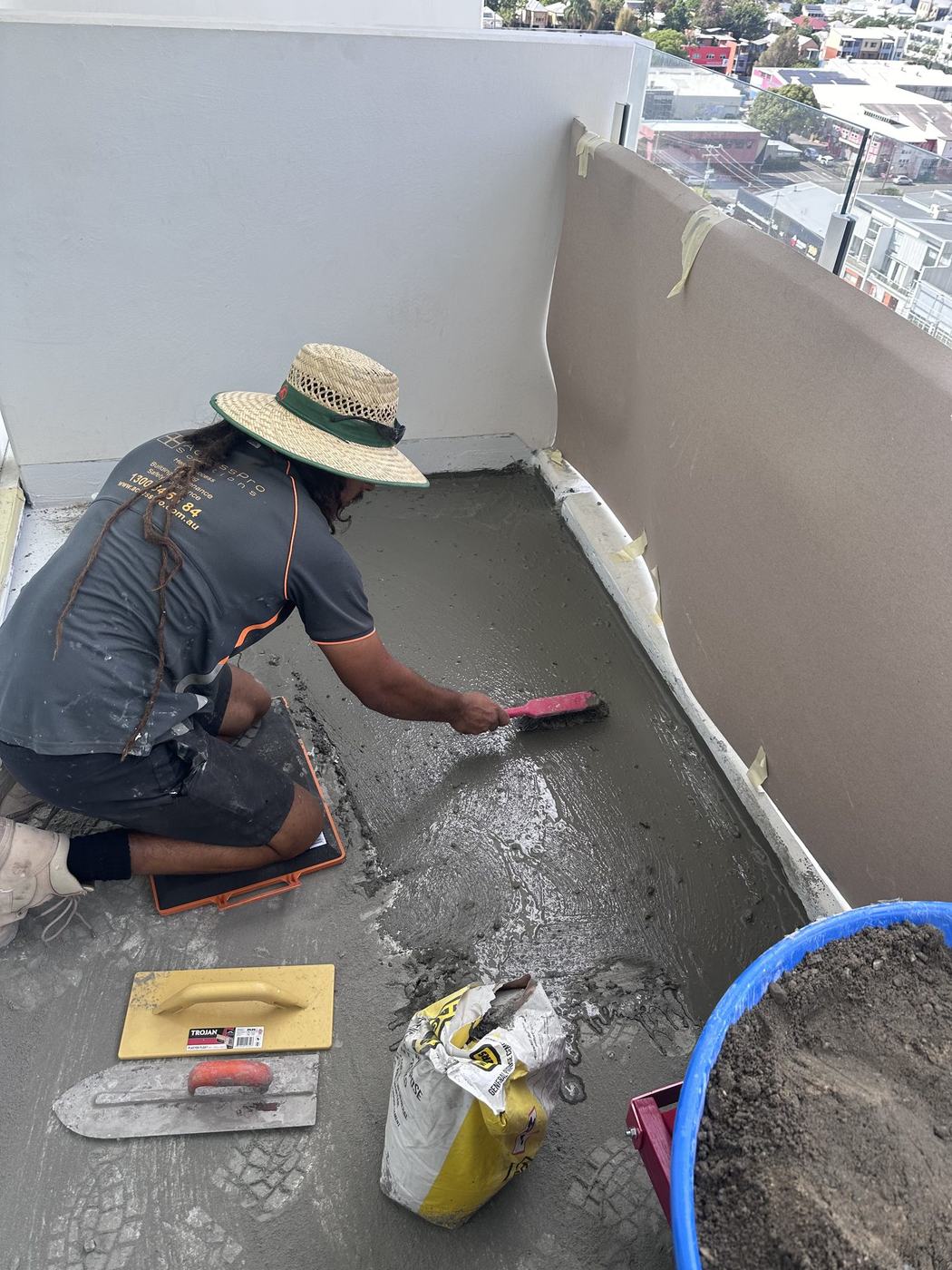 Hydro-Tec tradesman laying screed on a high-rise balcony