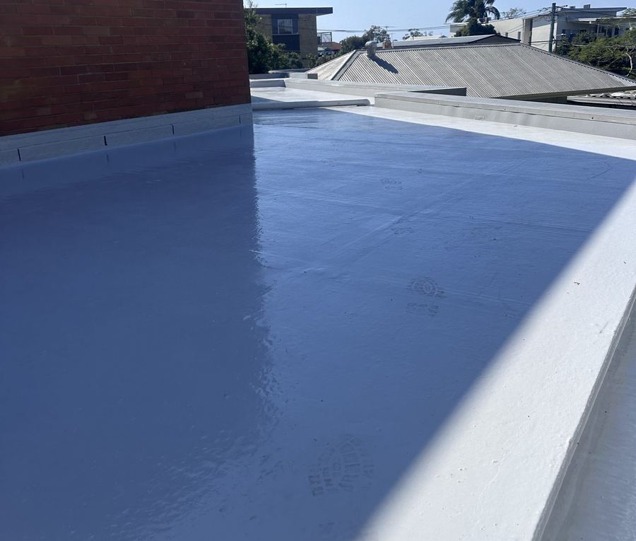 New waterproofing membrane on a rooftop deck beside a brick wall
